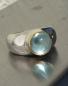 Preview: Ein runder, himmelblau strahlender Edeltopascabochon in Gold gefasst auf einem Silberring