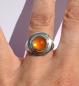 Preview: Der Feueropalcabochon ist in Silber gefasst und wird von einem goldenen Band umlaufen.