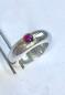 Preview: Ein runder rosaner Rhodolithcabochon ist in einer Goldfassung aus 750er Gold gefasst und sitzt auf einer kräftigen und aus einem Stück gegossenen Ringschiene aus 935er Silber.