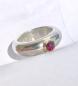 Preview: Ein runder rosaner Rhodolithcabochon ist in einer Goldfassung aus 750er Gold gefasst und sitzt auf einer kräftigen und aus einem Stück gegossenen Ringschiene aus 935er Silber.