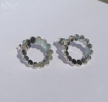 Zwei runde Ohrstecker aus aneinander gereihten Silberplättchen, die wie aneinanderliegende Blütenblätter wundervoll glitzern und funkeln.