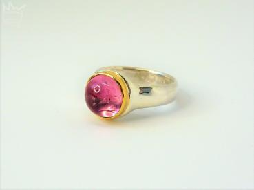 Preview: Ein wundervoller, runder,rosaner Turmalin mit lebendigen Wachstumsspuren, in 750er Gelbgold gefasst, sitzt auf einer Ringschiene in 935er Silber.