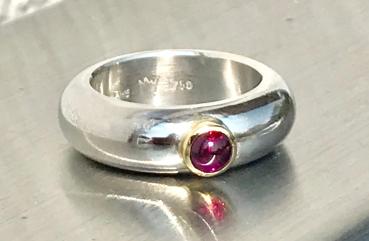 Ein runder rosaner Rhodolithcabochon ist in einer Goldfassung aus 750er Gold gefasst und sitzt auf einer kräftigen und aus einem Stück gegossenen Ringschiene aus 935er Silber.