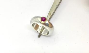 Preview: Ein runder rosaner Rhodolithcabochon ist in einer Goldfassung aus 750er Gold gefasst und sitzt auf einer kräftigen und aus einem Stück gegossenen Ringschiene aus 935er Silber.