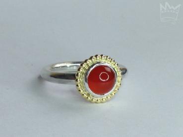 Ein runder, zinnoberroter, wunderschöner Karneol, sitzt auf einem feinen Silbertellerchen und ist ebenfalls in Sterlingsilber gefasst. Um die Fassung läuft ein feiner Kugelkranz aus 18kt Gelbgold.