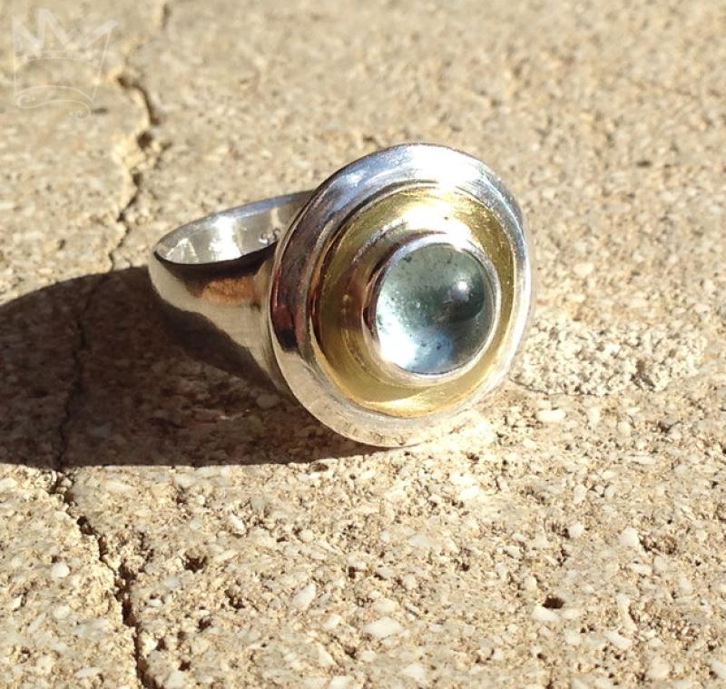 Ein wundervoller, zart hellblauer Edeltopas, eingebettet in ein goldenes Band, gefasst in Silber auf einer gegossenen Ringschiene ebenfalls aus 935er Silber.