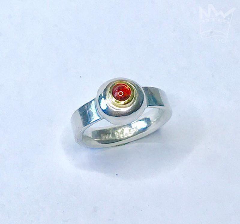 Ein wunderschöner, runder Granat als Cabochon geschliffen und in 18kt Gelbgold gefasst, sitzt auf einem grossen Silbernugget der in der Ringschiene aus 935er Silber sitzt.