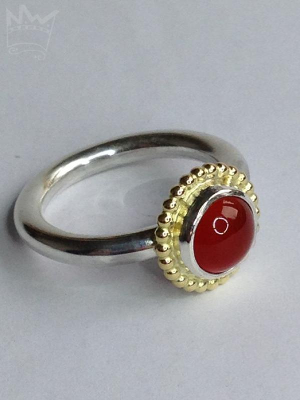 Ein runder, zinnoberroter, wunderschöner Karneol, sitzt auf einem feinen Silbertellerchen und ist ebenfalls in Sterlingsilber gefasst. Um die Fassung läuft ein feiner Kugelkranz aus 18kt Gelbgold.
